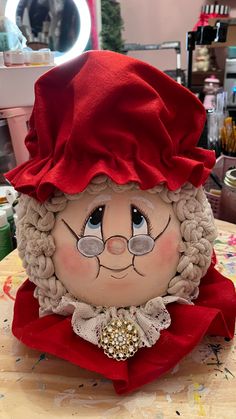 a close up of a stuffed animal wearing a red hat and dress on a table