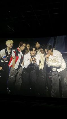 a group of young men standing next to each other in front of a black background