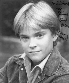 a black and white photo of a young boy with blonde hair wearing a denim jacket