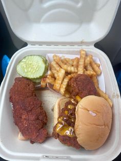 a foam container filled with chicken, fries and pickle wedges next to a sandwich