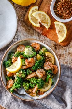 a bowl filled with shrimp, broccoli and lemon slices