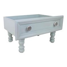 a white drawer with two knobs on the front and one in the middle, sitting on