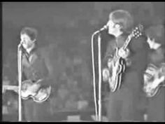 two men singing into microphones while holding guitars