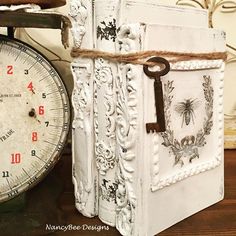 an old clock sitting next to a white book