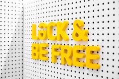 yellow letters that say lock and be free on a white wall with black polka dots