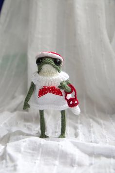 a crocheted frog wearing a santa hat and dress