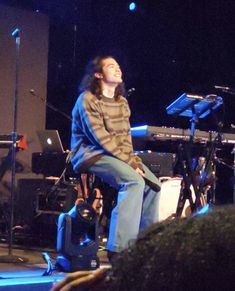 a man sitting on top of a stool in front of a microphone