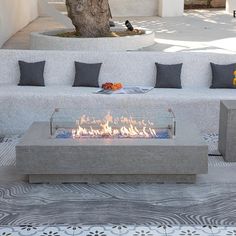 a fire pit sitting in the middle of a patio with pillows on it's sides