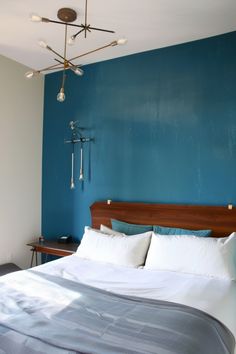 a bed with blue walls and white sheets in a room that has a wooden headboard