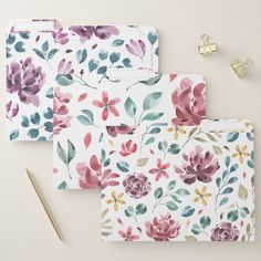 three floral patterned folders next to a pen