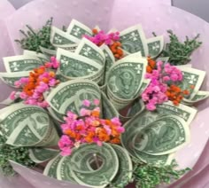 a bunch of money with pink flowers in it on top of purple tissue paper wrapped around the dollar bills