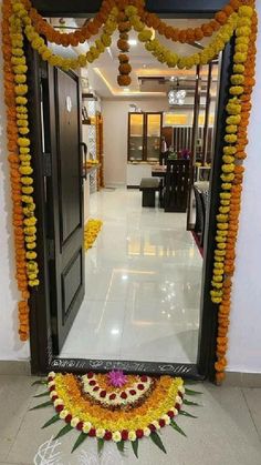 an entrance decorated with orange and yellow garlands, flowers and candles on the floor