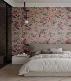 a large bed sitting next to a pink wall with flowers on it and two lamps hanging from the ceiling