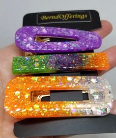 there are three cell phones in the palm of someone's hand, each with different colored glitters on them