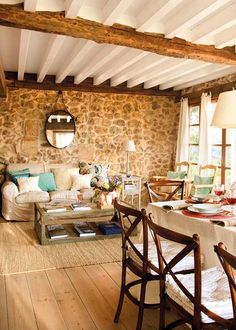 a living room filled with furniture next to a stone wall and wooden floored walls