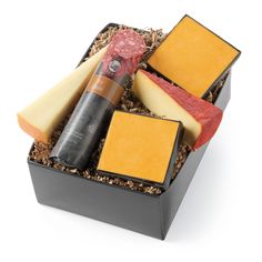 an assortment of cheese, meat and wine in a black box on a white background