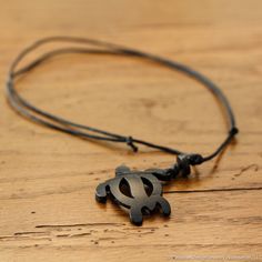 a black necklace with a metal symbol on it