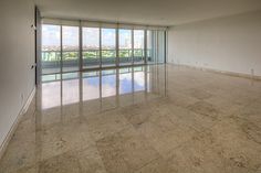 an empty living room with large windows and marble flooring in front of a city view