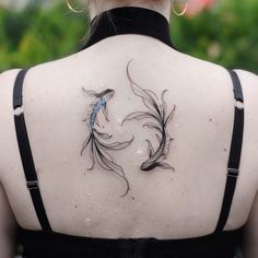 the back of a woman's neck with two koi fish tattoos on it