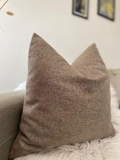 a brown pillow sitting on top of a couch next to a vase with flowers in it