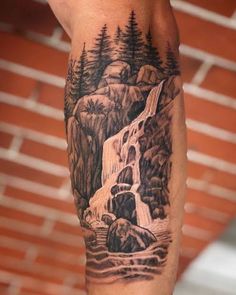 a man's arm with a waterfall and trees on it