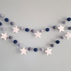 a string of felt stars hanging from the ceiling with blue and white balls on it