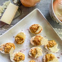 several deviled eggs on a white plate with garlic and seasoning next to them