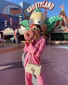 a woman holding a doughnut up to her face while standing in front of a simpsons sign