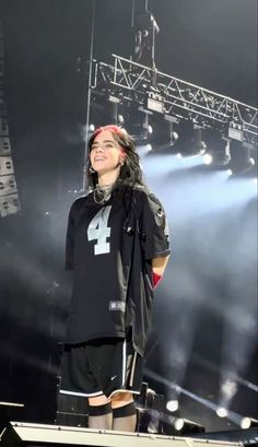 a man standing on top of a stage with his arms in the air and wearing knee high boots