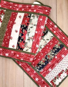 three placemats with red, white and green designs on them sitting on a wooden surface