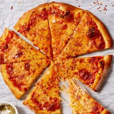 a sliced pizza sitting on top of a table next to a bowl of sauce and a fork