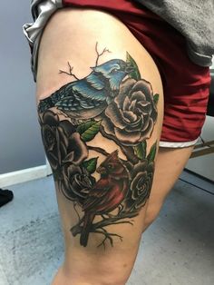 a woman's thigh with roses and a bird on the top of her leg