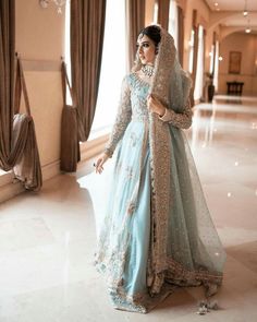 a woman in a blue and gold wedding dress posing for the camera with her hand on her hip