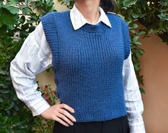 a woman wearing a blue sweater vest and black pants