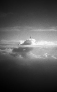 a person standing on top of a cloud in the middle of black and white photo