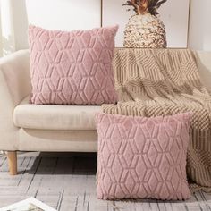 two pink pillows sitting on top of a white couch next to a pineapple pillow