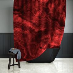 a red and black shower curtain in an empty room with stools next to it