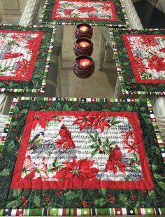 a quilted table runner with candles on it and poinsettis in the center