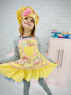 Your little girl will love to help out in the kitchen when she is dressed in this adorable apron set. It features a pretty ruffled skirt and small pocket. This apron would also be a great gift to go along with a pretend kitchen or tea party set. You may choose to add a matching chef's hat to this apron. It has a Velcro closure which makes it adjustable. The band is finished with a strip of rick rack and a removable fabric flower pin. The body of this apron is made with a shabby chic vintage looking floral pink in Yellow and pink. The ruffle and pocket are made with a coordinating light pink micro dot cotton fabric. It is trimmed with baby pink mini polka dot handmade bias tape. Girls Apron, Tea Party Set, Fabric Flower Pins, Ruffle Apron, Pretend Kitchen, Toddler Apron, Tea Party Setting, Girl Apron, Childrens Aprons