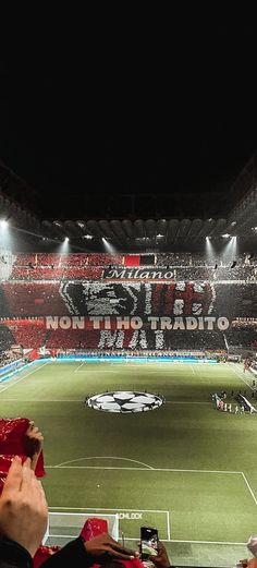 a stadium filled with lots of people watching a soccer game on the field at night