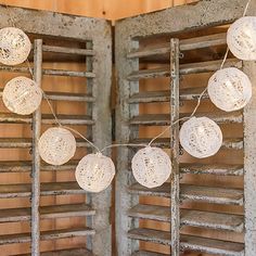 some white balls are hanging from the side of an old wooden window sill with shutters