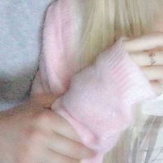 a close up of a person wearing a sweater and holding a pink mitten in their hand