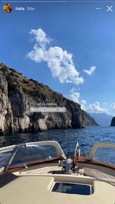 an image of a boat on the water with mountains in the back ground and clouds in the sky