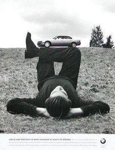 a man laying on the ground in front of a car