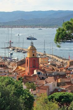 an aerial view of a city with boats in the water and mountains in the background