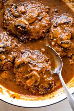 two meat patties covered in gravy with a spoon