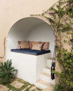 a bench with pillows on it sitting in the middle of a garden next to stairs