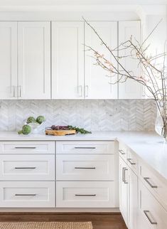 a kitchen with white cabinetry and counter tops, along with a vase filled with flowers