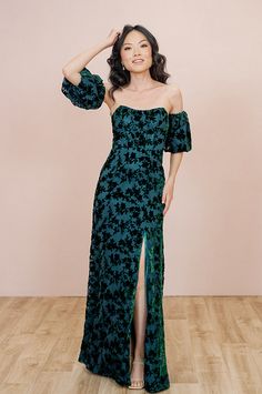 a woman in a green dress posing for the camera with her hand on her head