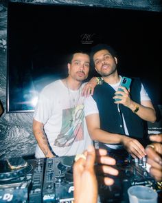 two men standing next to each other in front of a dj's turntable